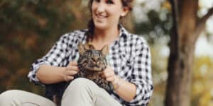 A woman sitting on a bench holding a cat.