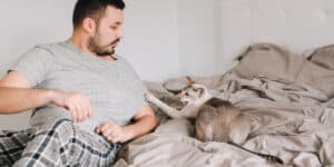A man laying in bed with a cat.
