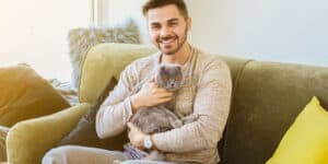 A man sitting on a couch holding a cat.