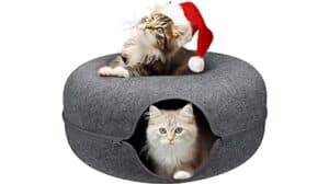 Two cats sitting in a cat bed with a santa hat.